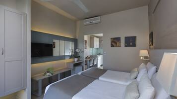 A modern hotel room with a bed, bedside tables, a desk, a chair, a TV, and a ceiling fan.