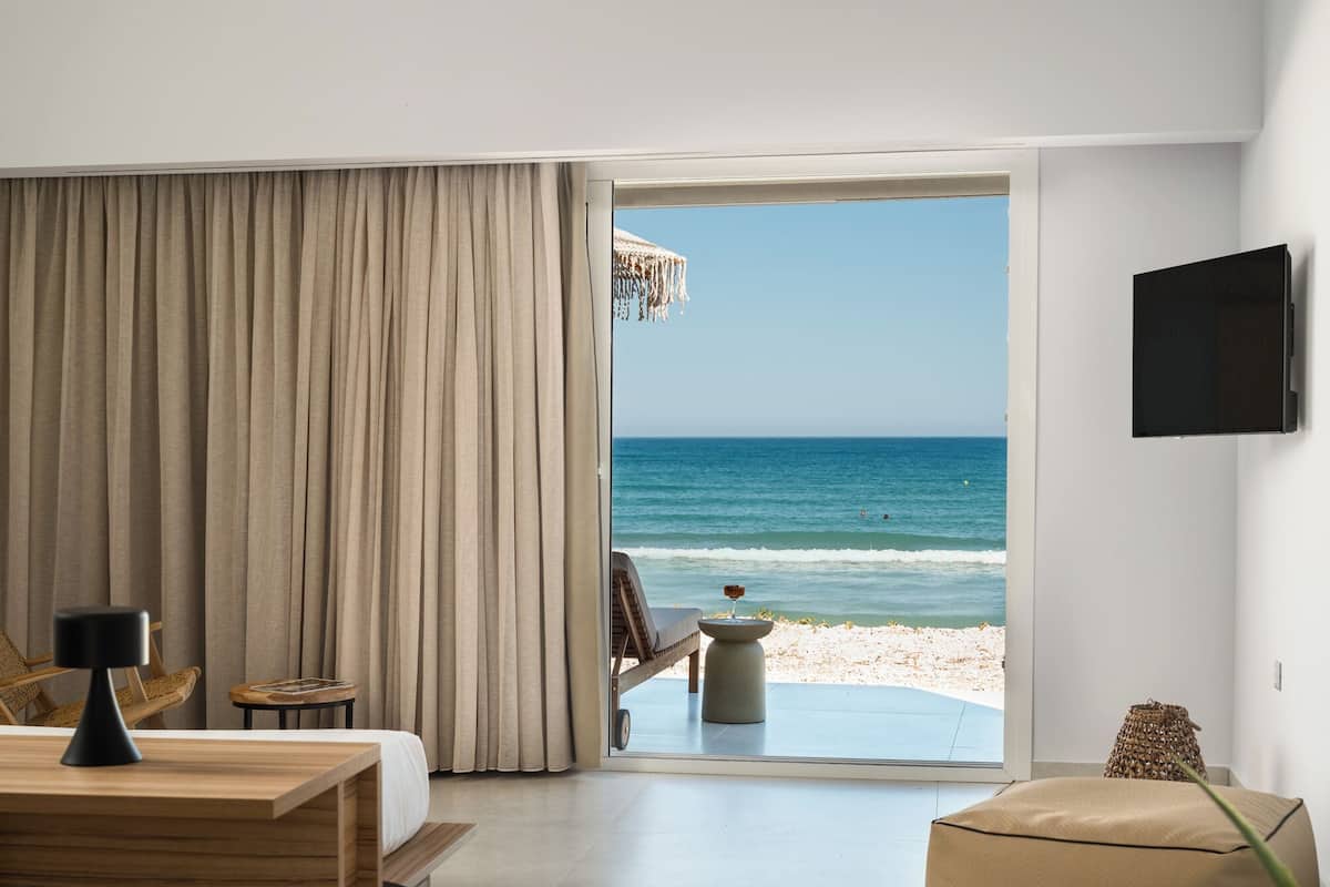 Ein Zimmer mit einem großen Fenster und Blick auf Strand und Meer.