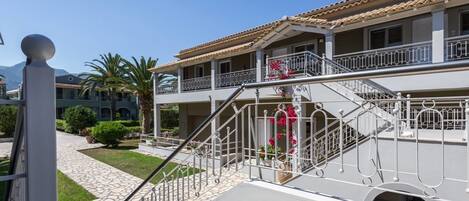 A hotel with a two-story structure, a stone pathway leading to the entrance, and a balcony with metal railings.