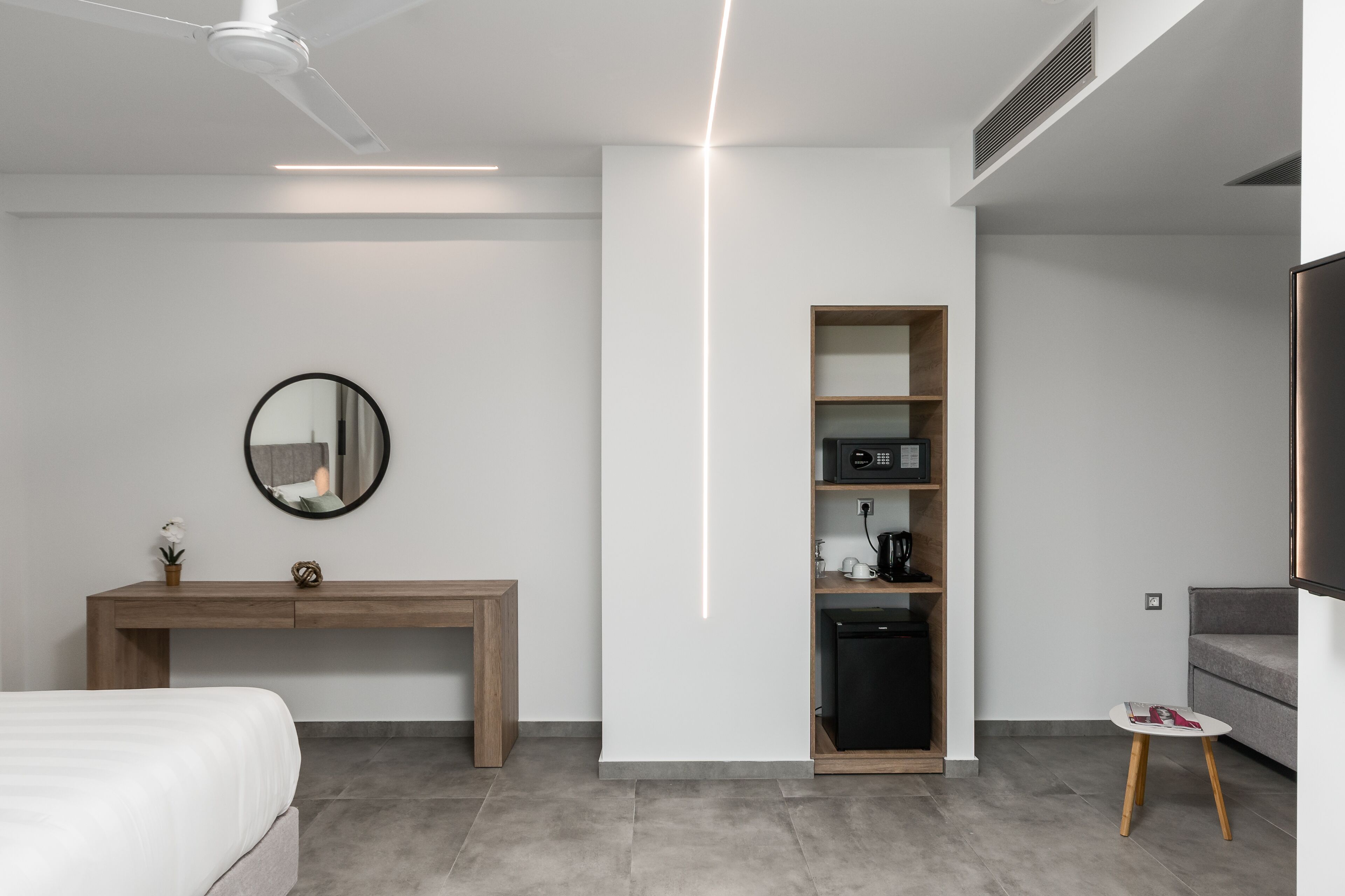 Ein modernes Hotelzimmer mit Bett, Holzschreibtisch, Einbauschrank, kleinem Tisch und Fernseher.