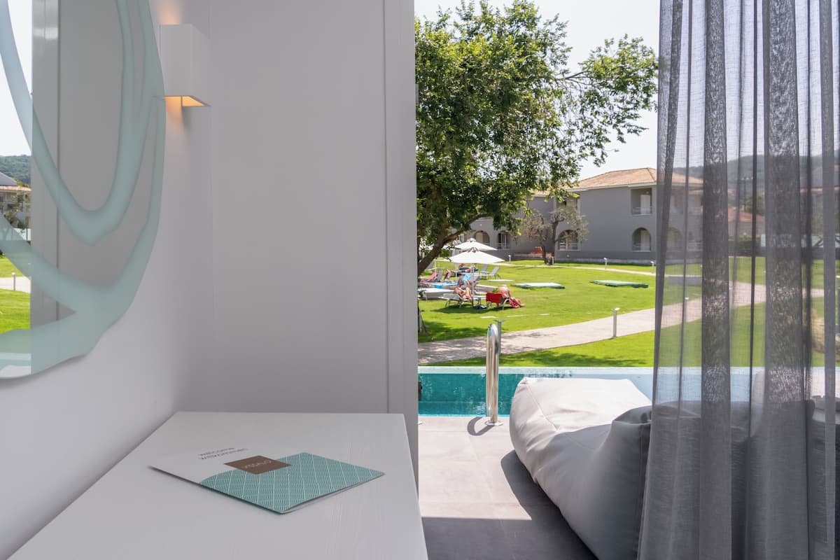 Ein modernes Hotelzimmer mit Blick auf einen Swimmingpool, einem großen Spiegel und einem ordentlich eingerichteten Schreibtisch.