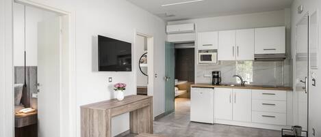 A modern kitchen with white cabinets, a built-in microwave, and a stainless steel range hood.