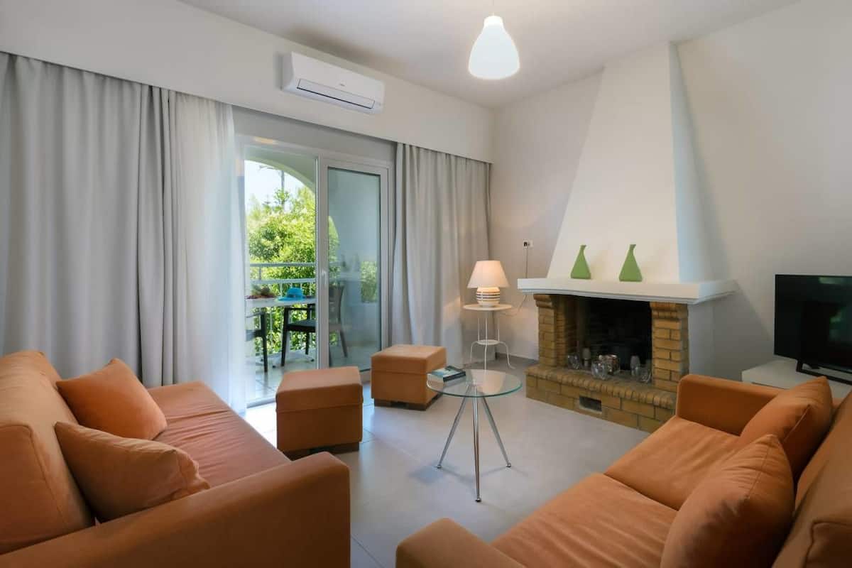 Una sala de estar moderna con chimenea, un conjunto de sofás y una televisión.