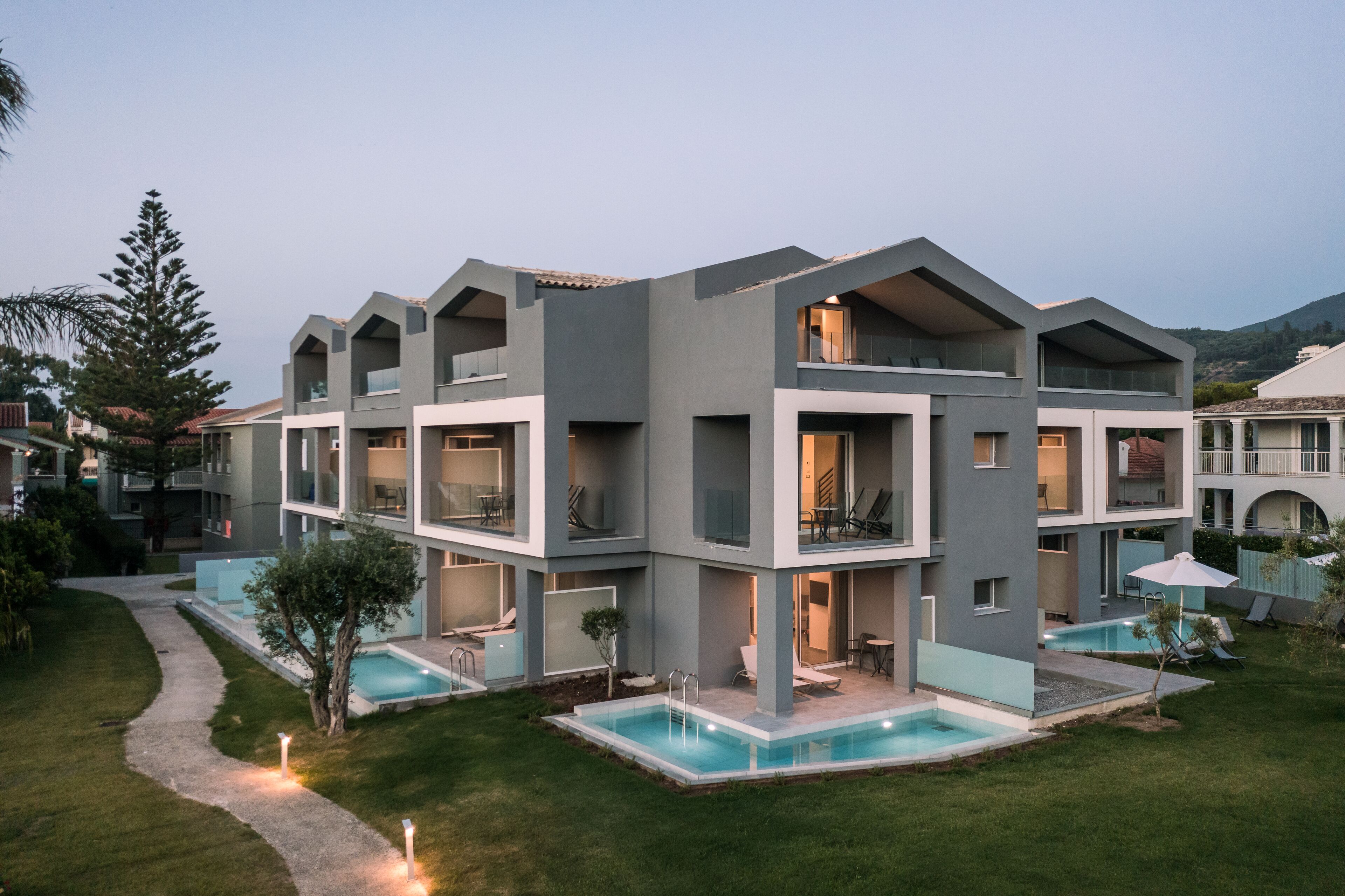 Un hôtel moderne à plusieurs étages, doté d’une piscine, d’un espace extérieur aménagé et d’une pelouse bien entretenue.