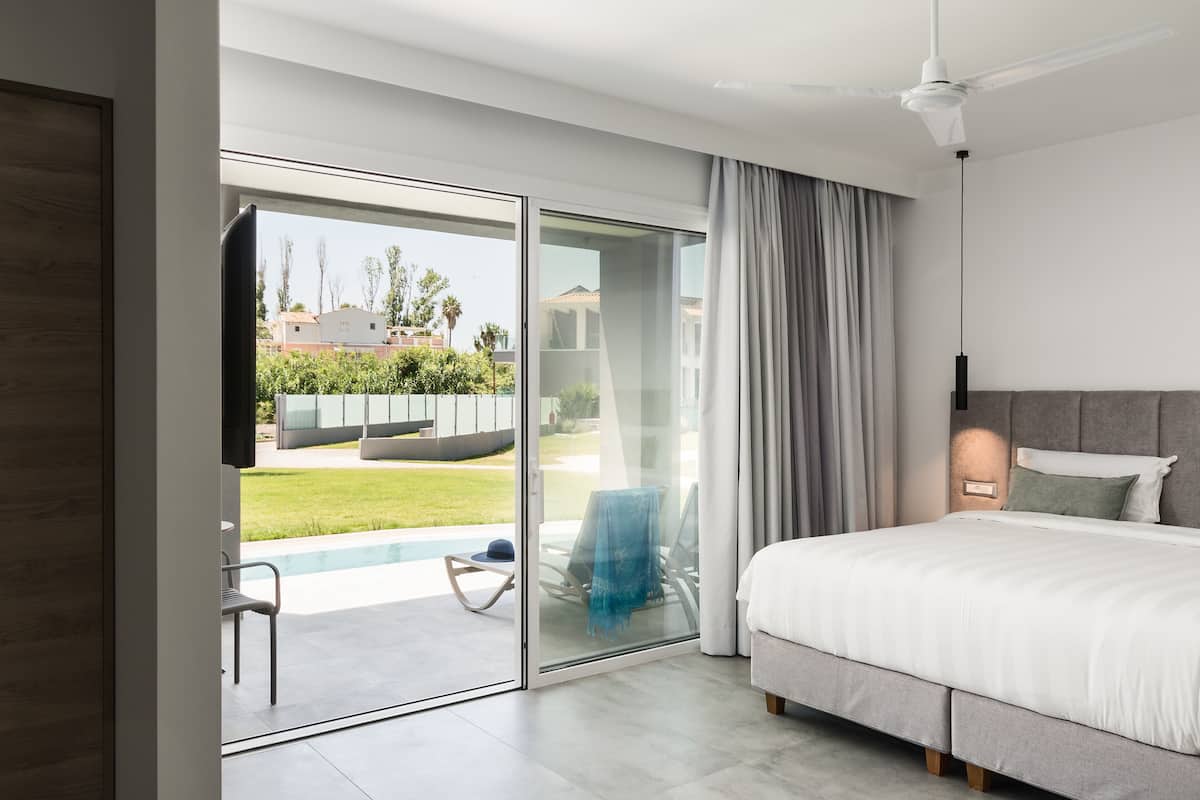 Ein modernes Schlafzimmer mit einem großen Bett, einer Schiebetür zu einem Balkon und einem Deckenventilator.