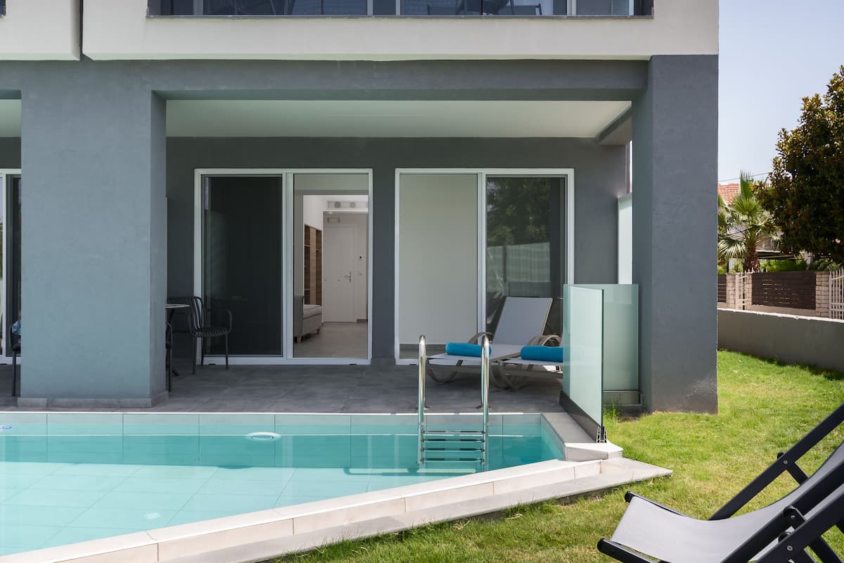 Ein modernes Gebäude mit Swimmingpool, Glastüren zu einer überdachten Terrasse und Liegestühlen.