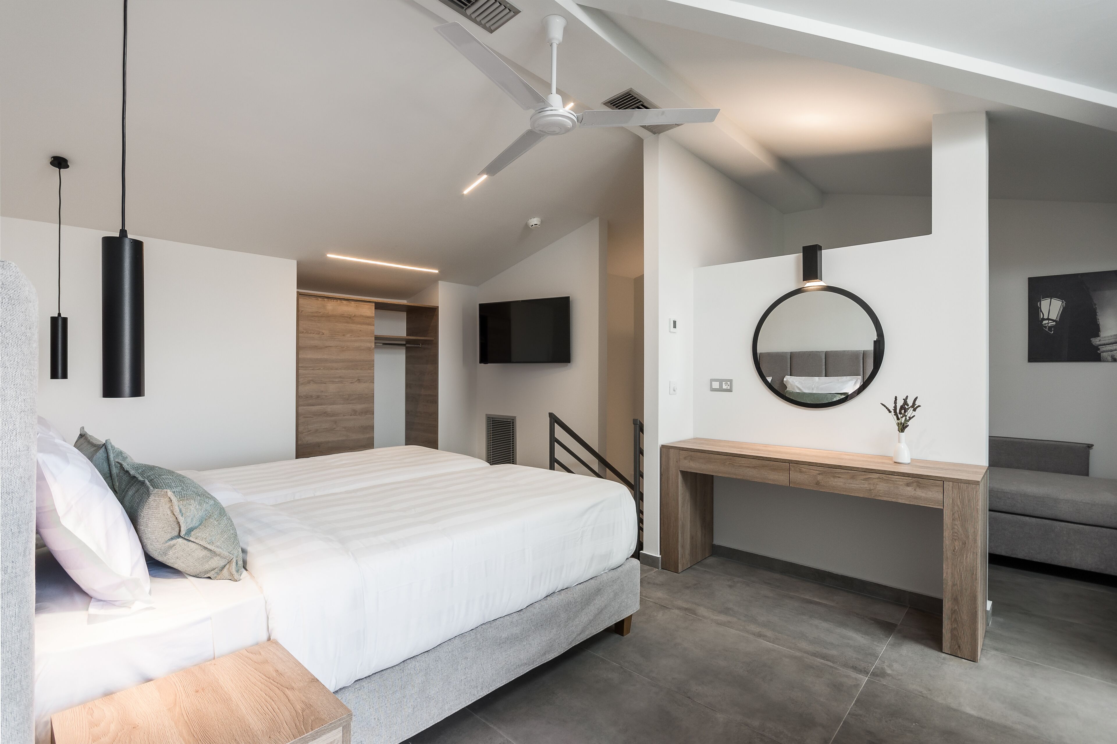 A modern bedroom with a bed, bedside table, and a desk with a mirror.