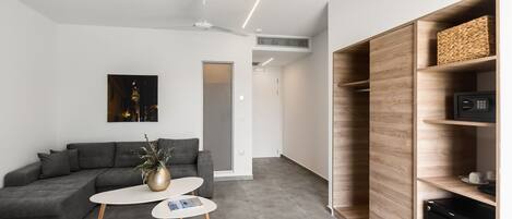A modern living room with a grey sectional sofa, a white coffee table, and a black entertainment unit.
