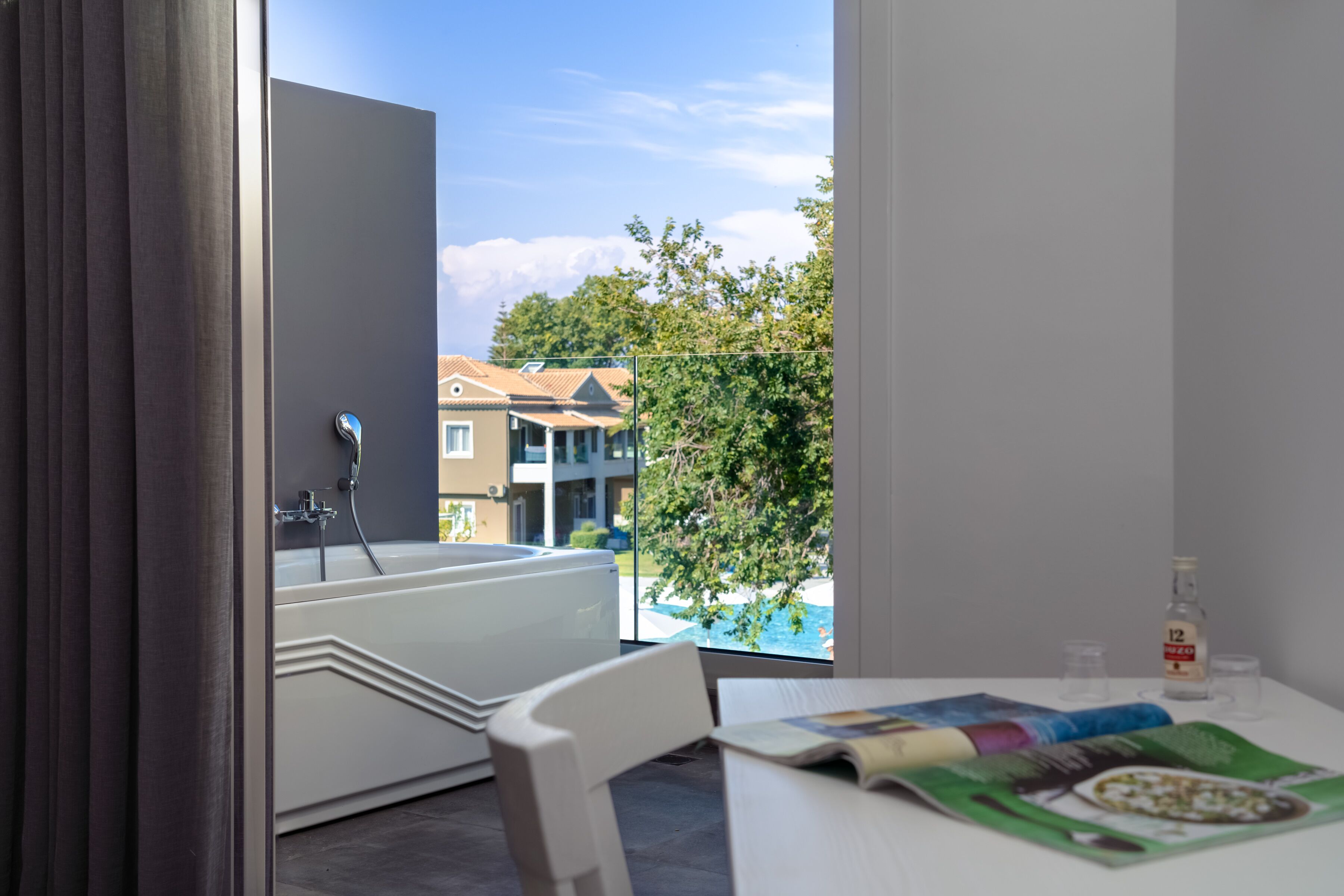 Un baño moderno con bañera, ducha y vistas a una piscina y edificios.