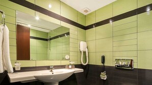 A bathroom with a large sink, a mirror, a hairdryer, and a toilet.