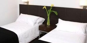 A hotel room with two single beds, a dark headboard, and a small table with a vase of flowers. - Cordoba 860 Suites (Buenos Aires)