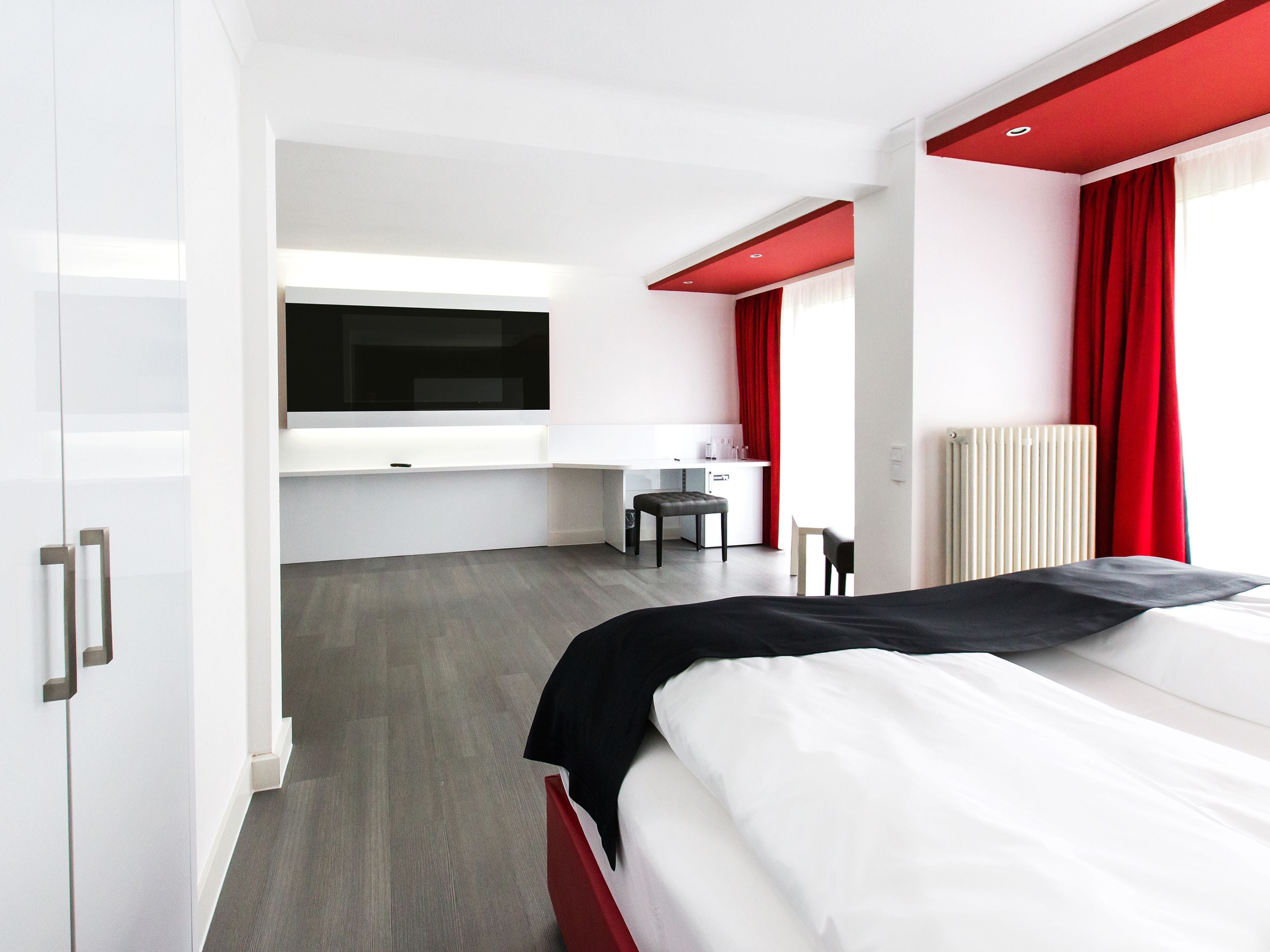 A modern hotel room with a bed, a desk, and a TV.