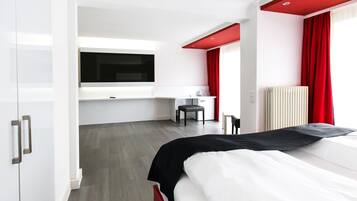 A modern hotel room with a bed, a desk, and a TV.
