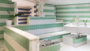 Un baño moderno con azulejos verde y blanco, encimera de mármol, bañera y lavamanos.