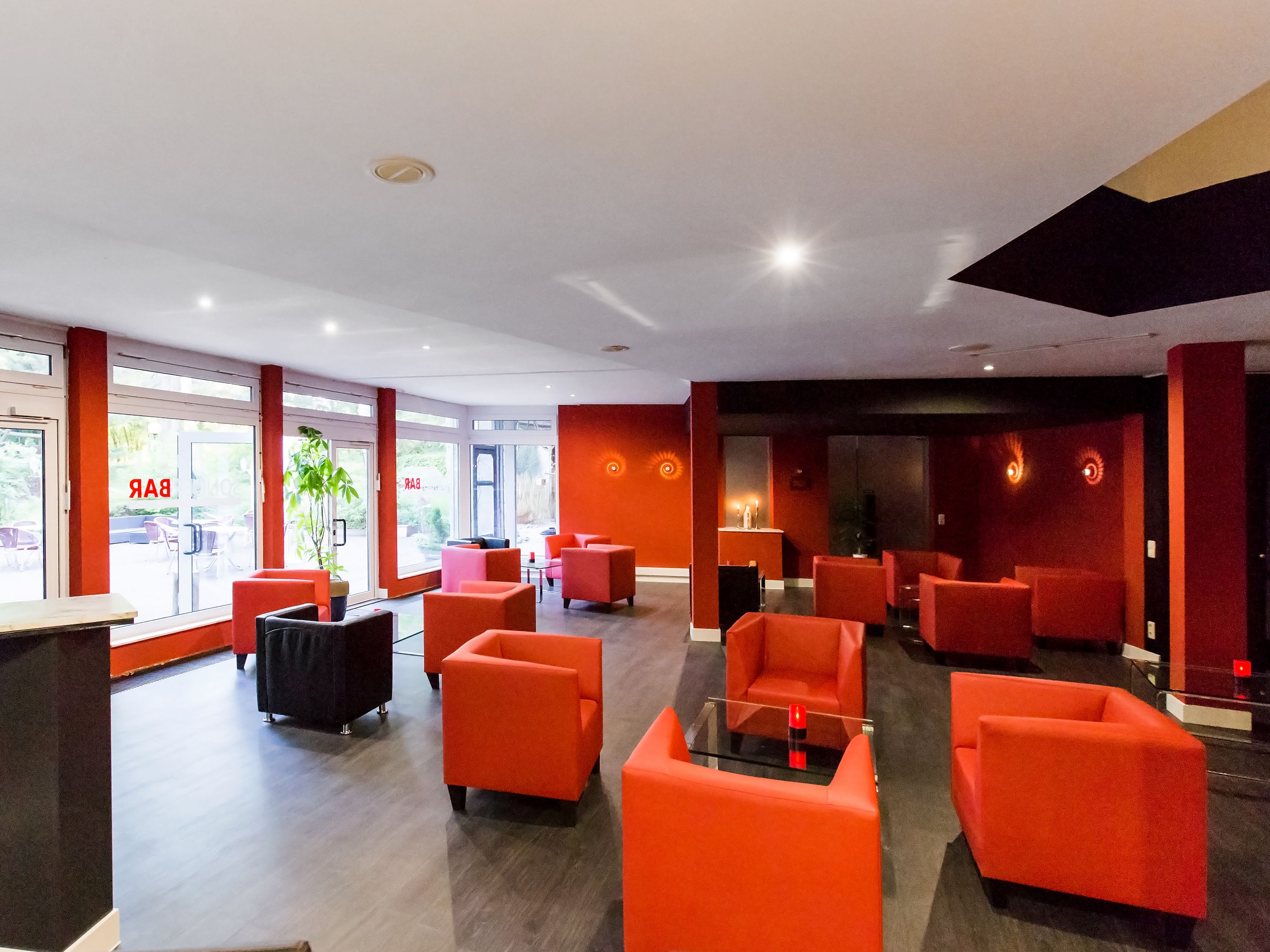 Un'accogliente hall moderna con posti a sedere rossi, una reception e ampie finestre.