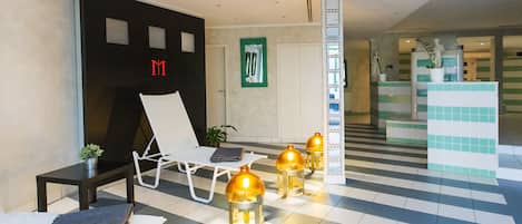 A modern waiting area with a lounge chair, a small table, and a potted plant.
