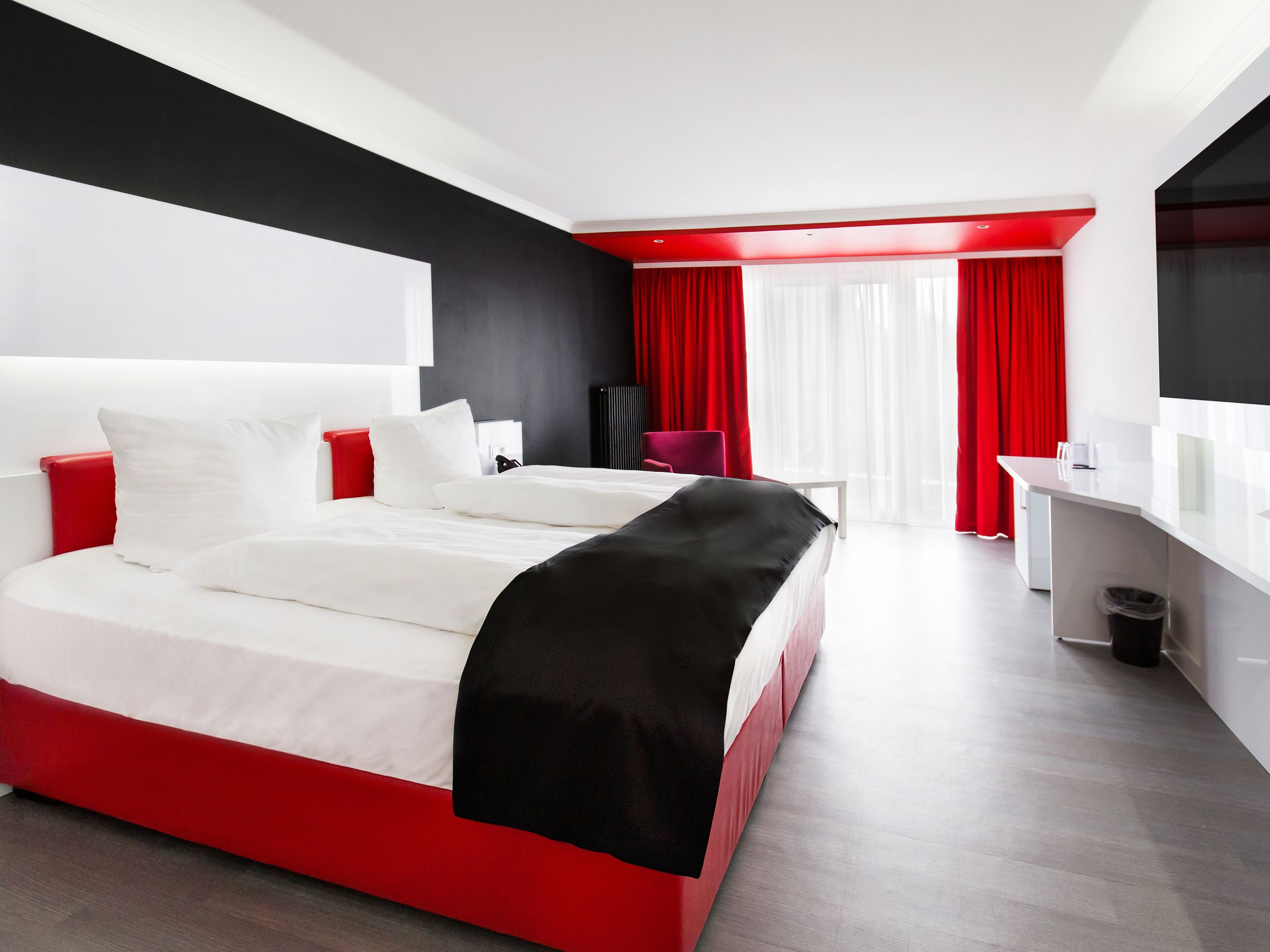 A modern hotel room with a large bed, a desk, and a chair.