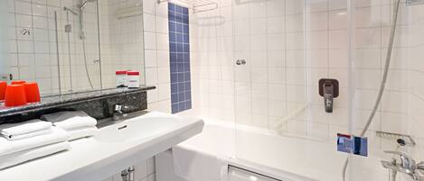 Un baño moderno con lavamanos blanco, espejo y cabina de ducha con paredes de vidrio.