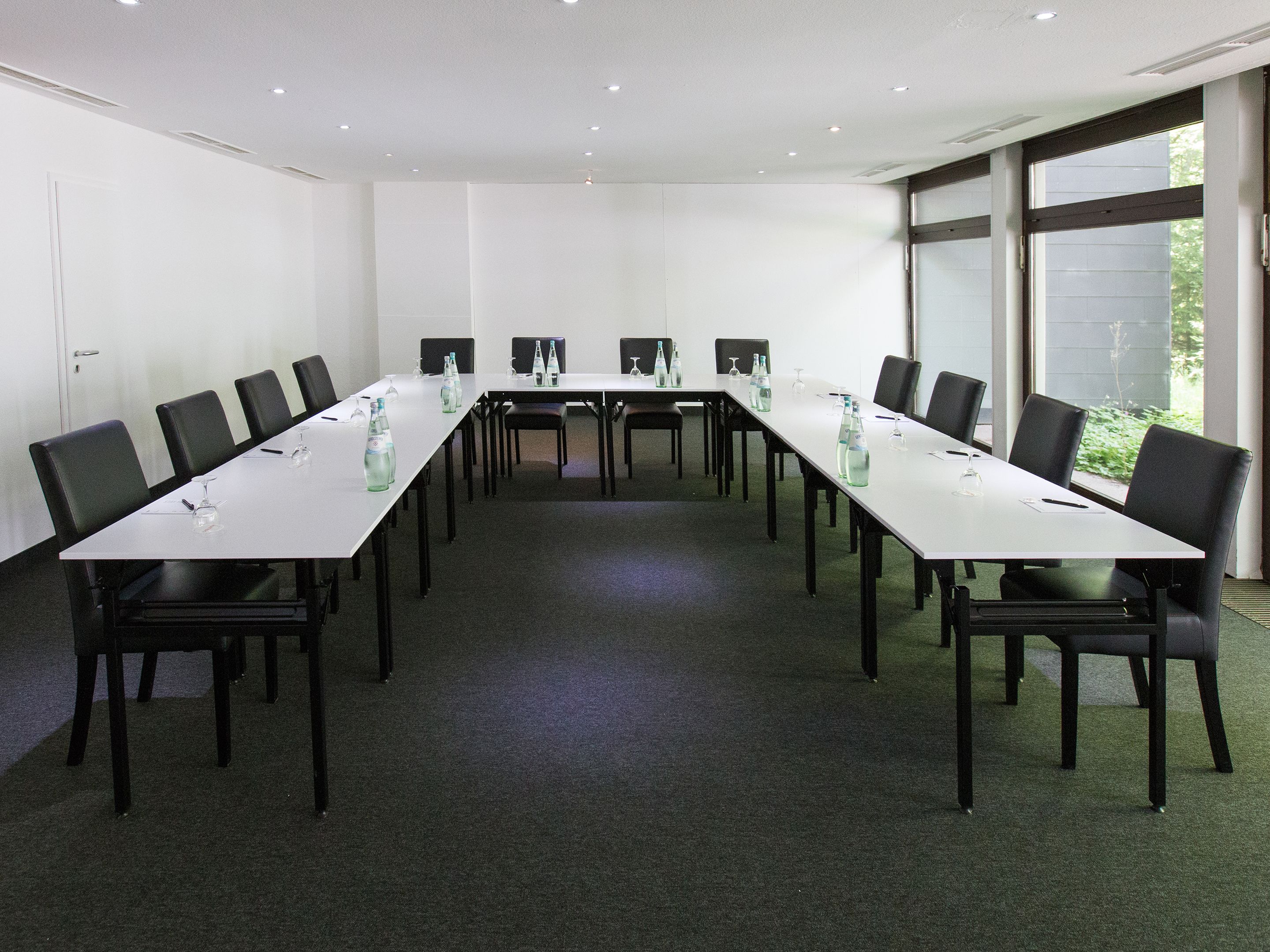 A conference room with a long table, chairs, and water bottles.