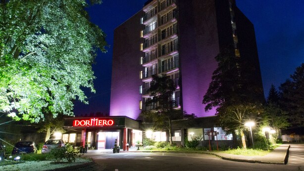Un edificio de varios pisos con un letrero que dice "DORMIREO" en la entrada.