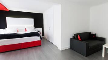 A modern hotel room with a large bed, a small sofa, and a desk.