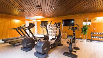 Un gimnasio con cintas de correr, elípticas y máquinas de pesas.