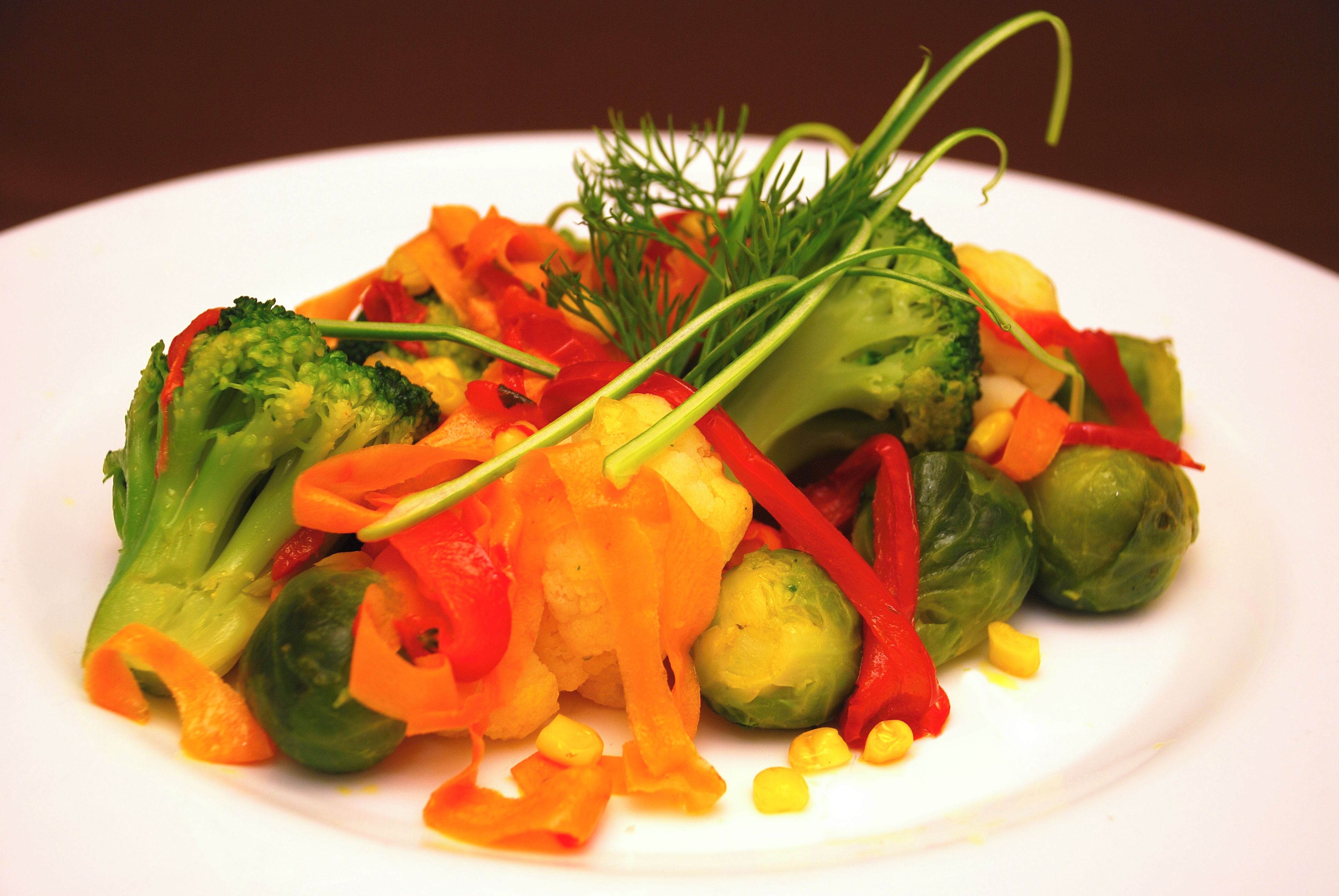 Un piatto di verdure miste, tra cui broccoli, carote e cavoletti di Bruxelles.
