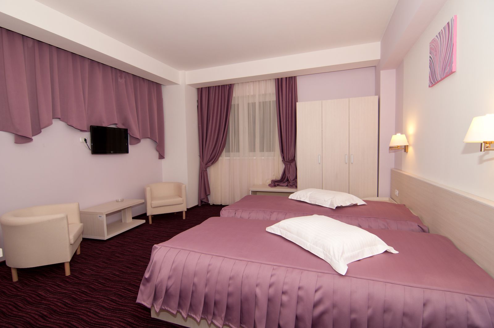Una habitación de hotel con una cama grande, un escritorio, una silla y un televisor.