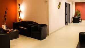Un espace d’accueil d’hôtel avec des sièges en cuir, un comptoir d’accueil et une plante en pot.