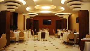 A banquet hall with round tables, chairs, and recessed ceiling lighting.