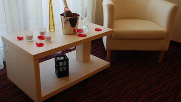A hotel room with a wooden table, a bottle of champagne, and a glass.