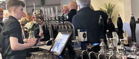 A bar area with multiple taps and a digital screen, likely for ordering drinks.