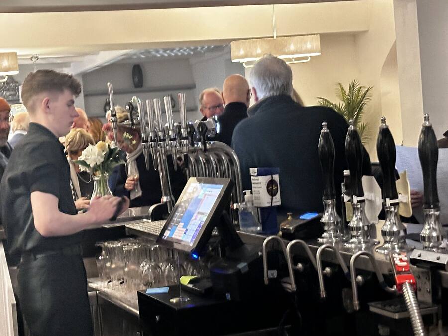 A bar area with multiple taps and a digital screen, likely for ordering drinks.
