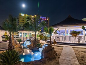 A nighttime resort with a pool, palm trees, and a bar area. - Vega Hotel (Constanta)