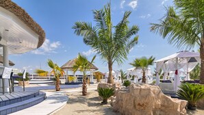 A resort with a pool area, palm trees, and beach chairs.