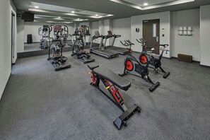 Une salle de sport équipée de divers appareils d’exercice, notamment des tapis de course, des vélos d’appartement et un banc de musculation.