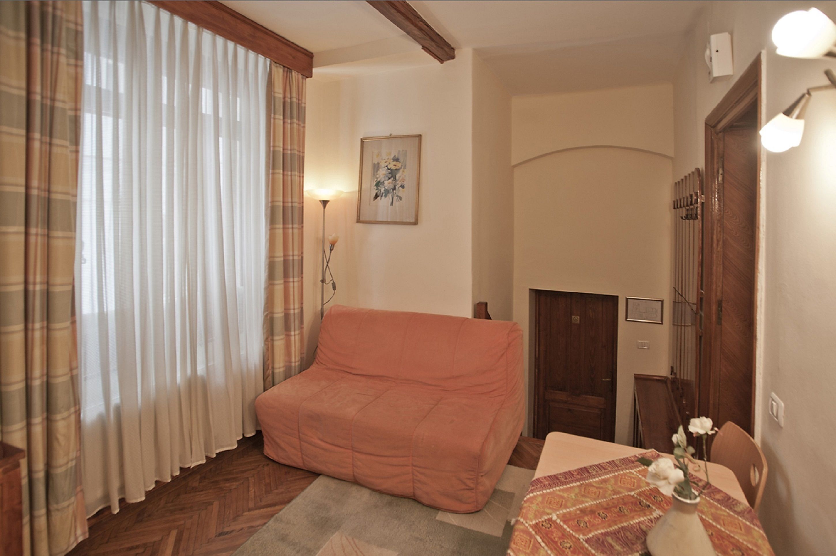 Una habitación acogedora con un sofá, una mesa con un florero y una puerta de madera.