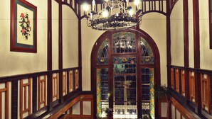 Un magnifique escalier, orné d’un lustre, de rampes en bois et d’une fenêtre à vitraux.