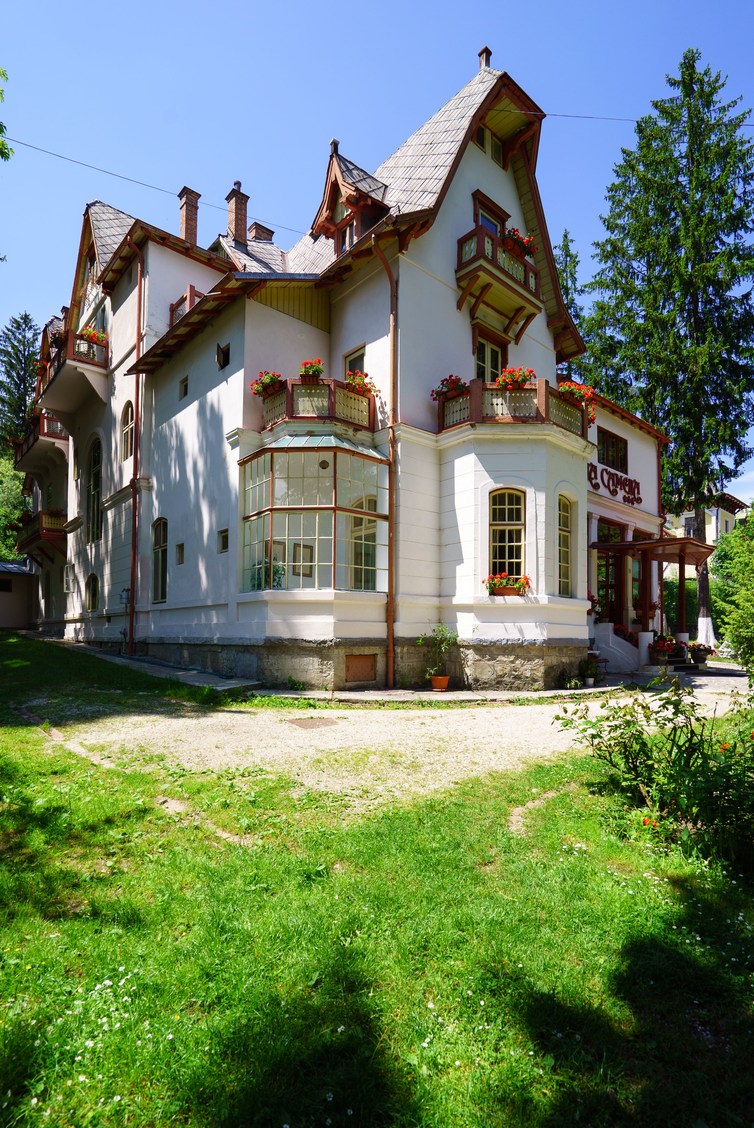 A traditional building with multiple windows, a balcony with flowers, and a clear sky.