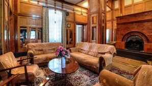 Une pièce de style traditionnel avec des boiseries, une cheminée et un ensemble de meubles de salon (canapé, fauteuils, etc.).
