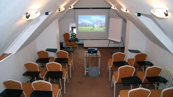 A conference room with a projector screen displaying a landscape image, arranged seating, and a presentation table.