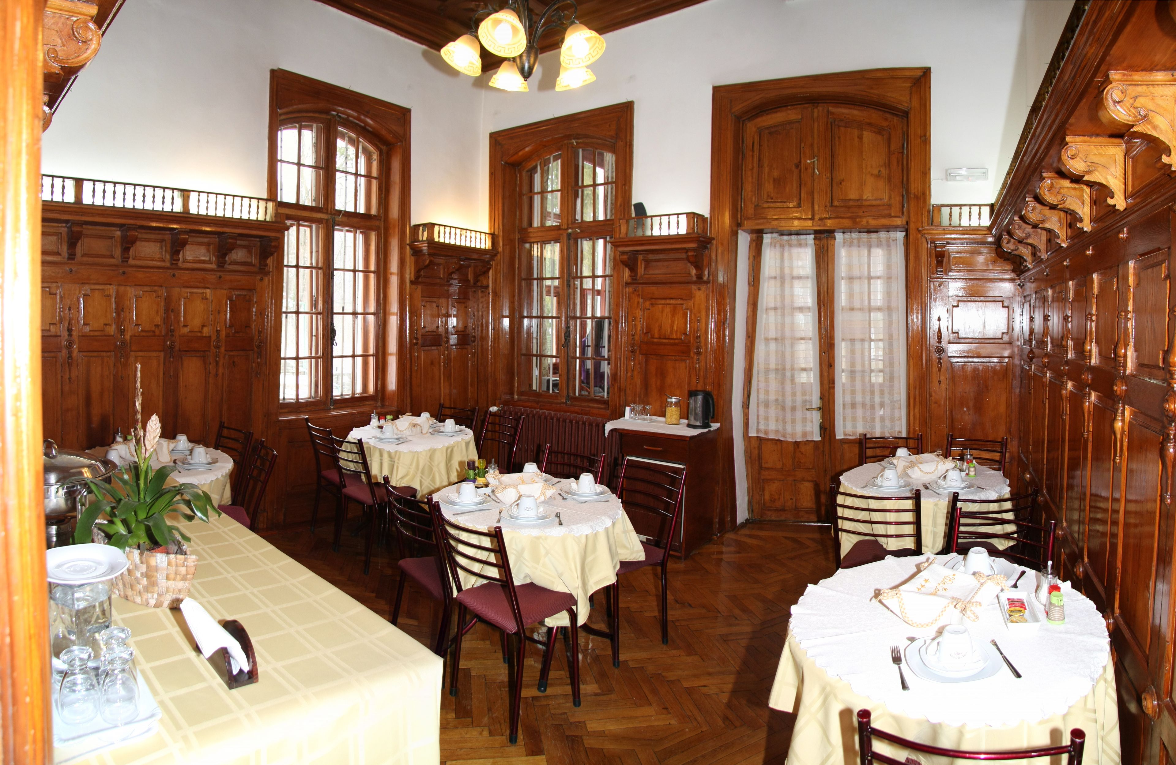 A dining area with wooden paneling, large windows, and round tables set for dining.