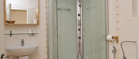 A modern bathroom with a glass-enclosed shower, a pedestal sink, and a toilet.