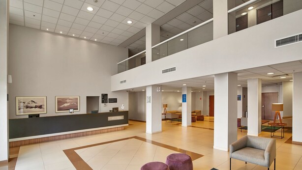 A spacious lobby with a reception desk, seating area, and a high ceiling with recessed lighting. - City Express by Marriott Puebla Angelopolis (Puebla)