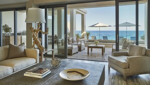 A spacious living room with a view of the ocean, featuring a sofa, armchairs, a coffee table, and a decorative tree sculpture. - Four Seasons Resort and Residences Anguilla (West End Village)