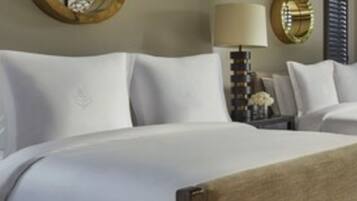 Quarto de hotel com uma cama grande, mesa de cabeceira com abajur e um espelho redondo na parede.