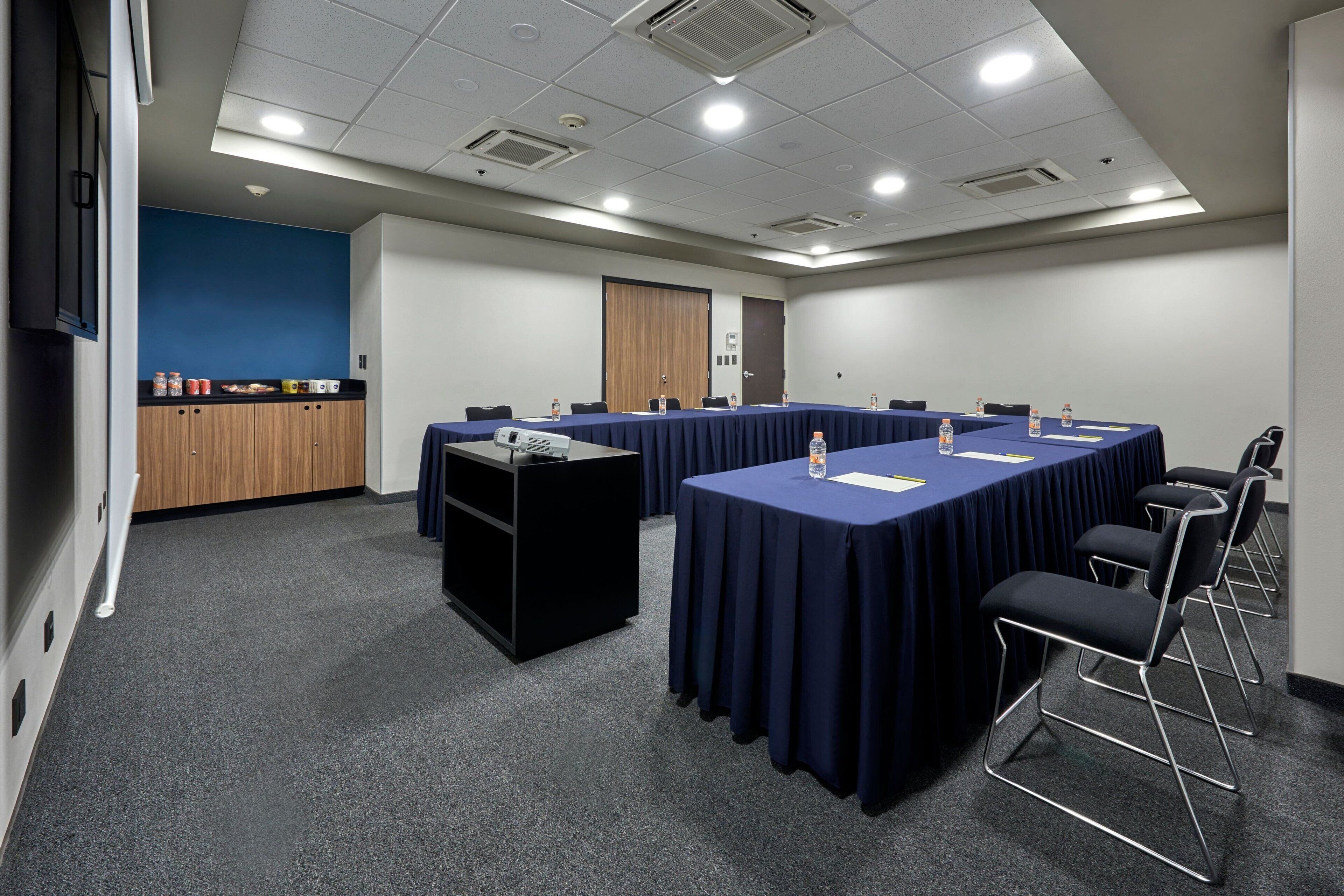 Un salón de conferencias con una larga mesa, sillas y un atril.