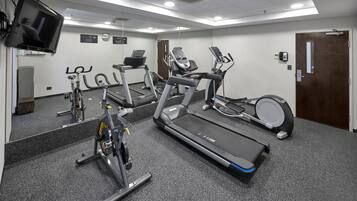 Un gimnasio con cintas de correr, elípticas y una bicicleta estática.
