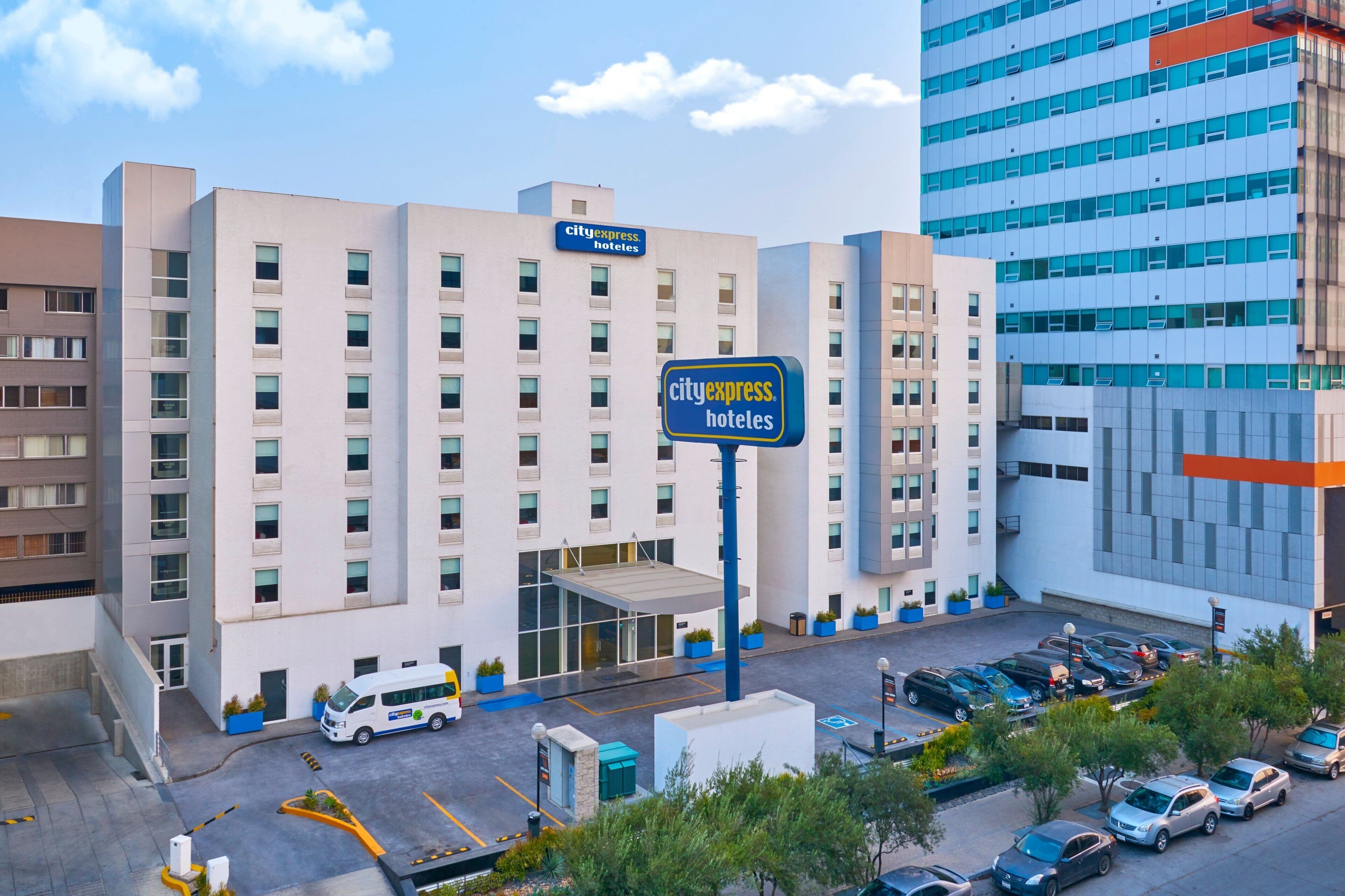 A CityExpress Hotel with a modern facade, multiple floors, and a parking lot with several cars.