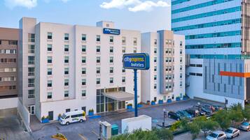 A CityExpress Hotel with a modern facade, multiple floors, and a parking lot with several cars.